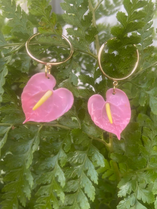 Culture Girl handmade, clay pink anthurium earrings with gold hoops on a green leafy background