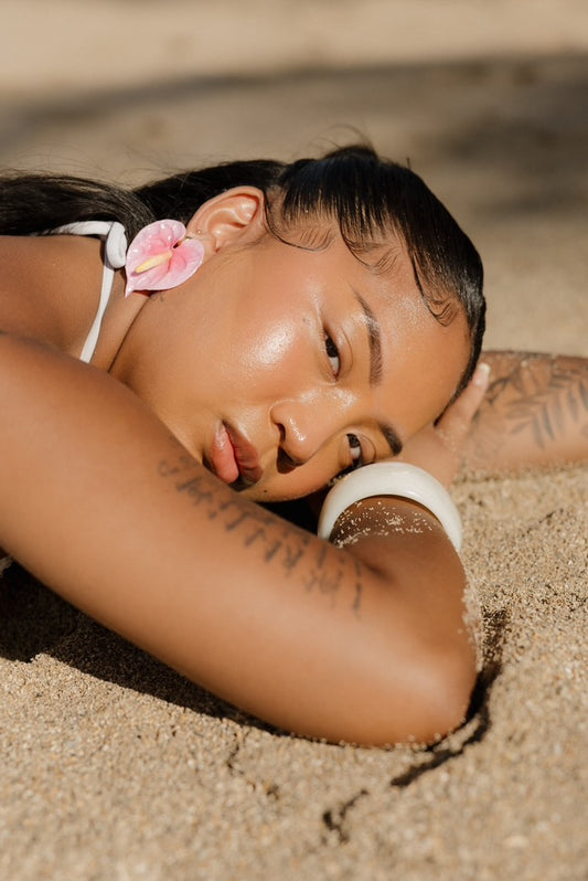 Model lying on sand wearing handmade anthrium thai earrings in hair
