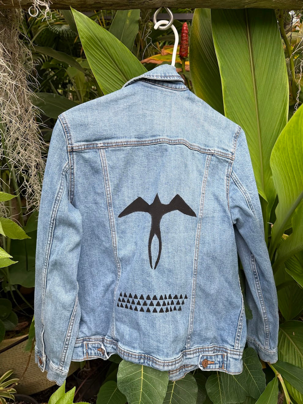 Hand-painted Iwa Bird and Lokahi Triangle on a light wash denim jacket