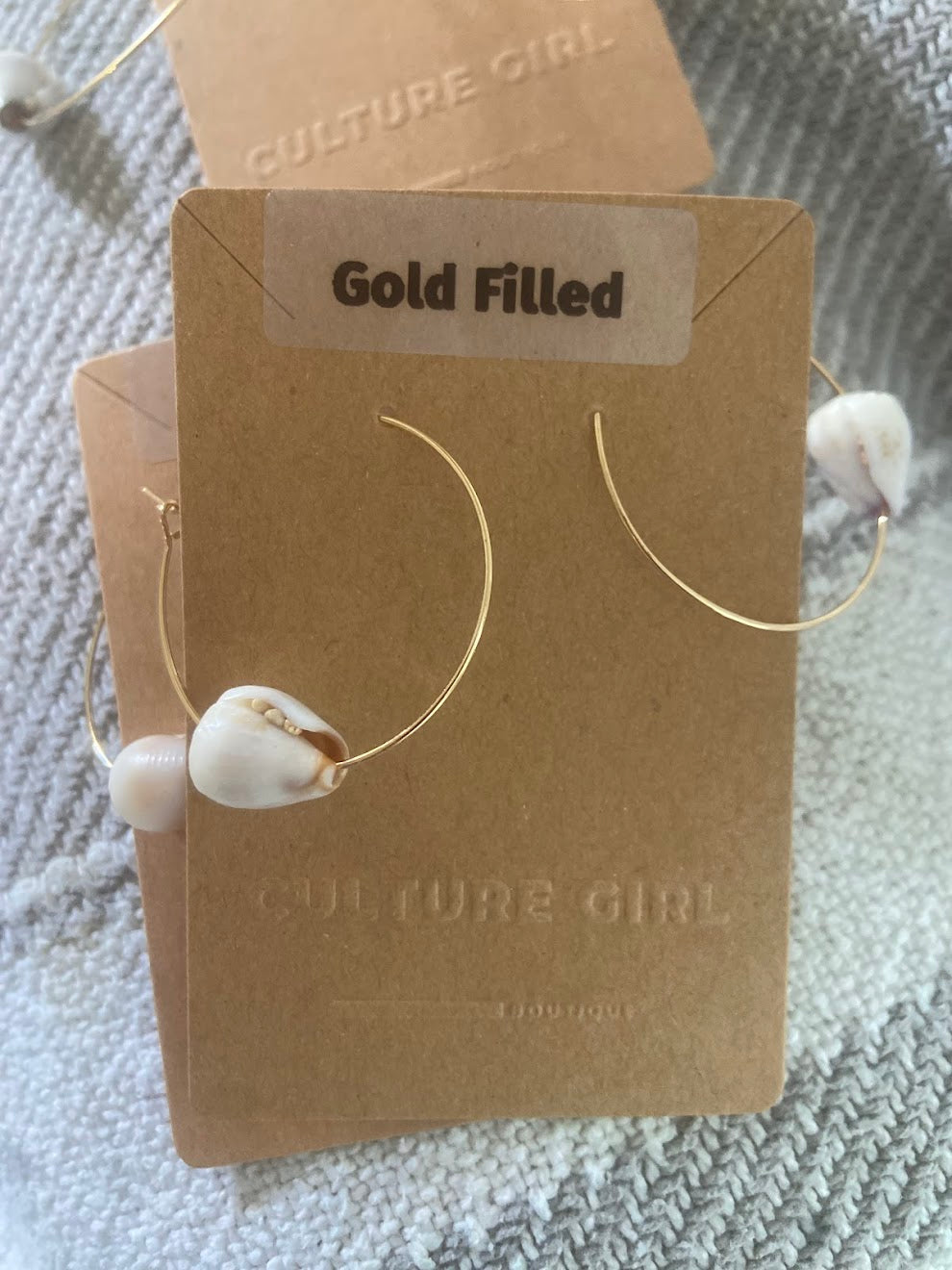 Gold filled earrings with shell accents on a 'Culture Girl' Boutique branded card.